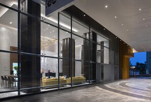 Un moderno vestíbulo de hotel con fachada de vidrio, zona de estar y mostrador de recepción.