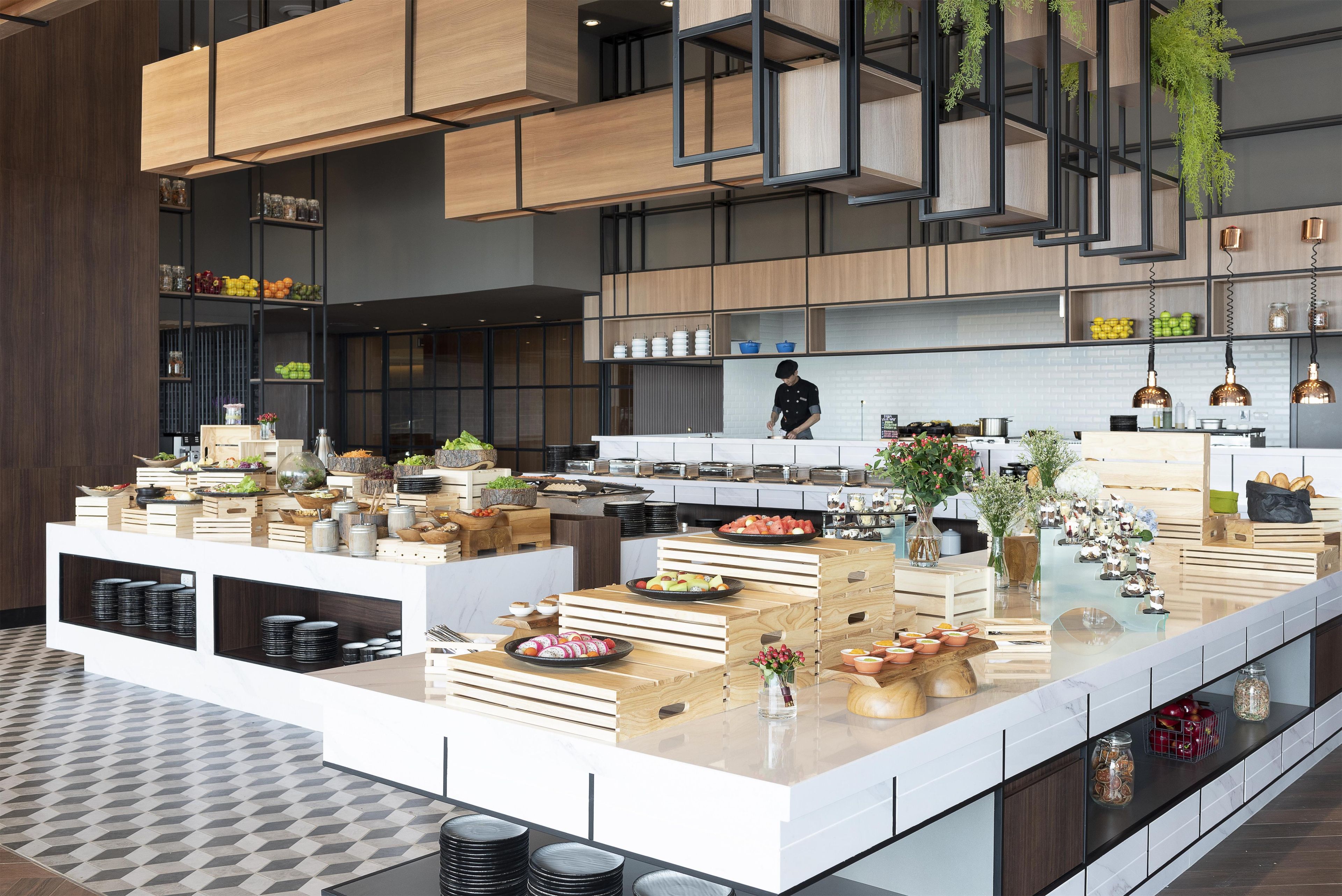 Une cuisine moderne avec des meubles en bois, un îlot central où sont présentés des aliments et des plantes suspendues.