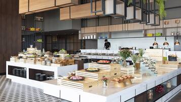 A modern kitchen with wooden cabinetry, a central island with food displays, and hanging plants.