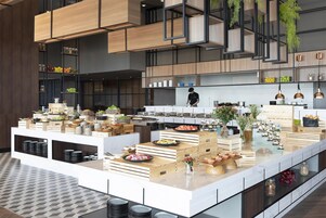 A modern kitchen with wooden cabinetry, a central island with food displays, and hanging plants.