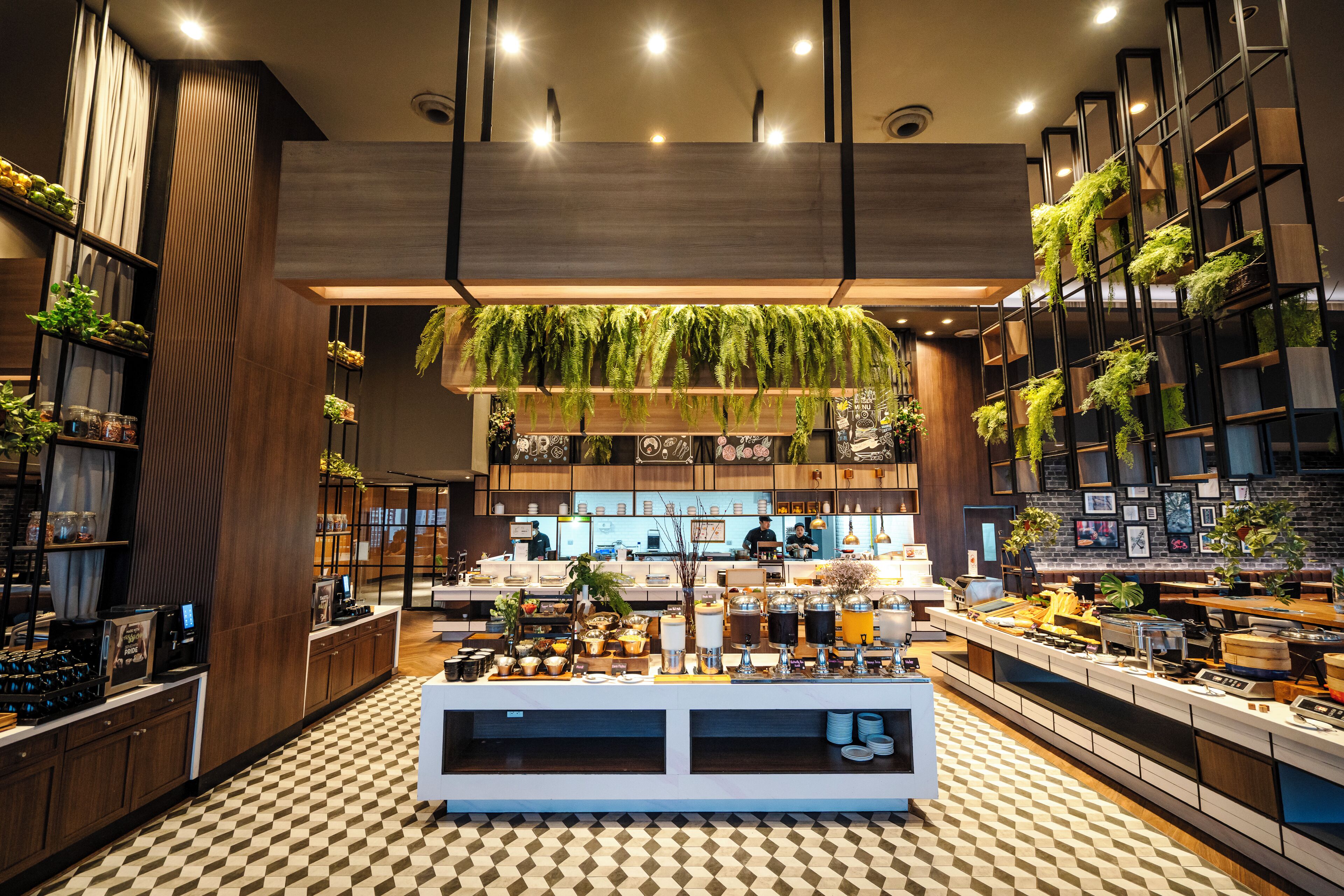 Eine moderne Hotelhalle mit Check-in-Schalter, Sitzbereichen und einer großen, hängenden Pflanzengestaltung.