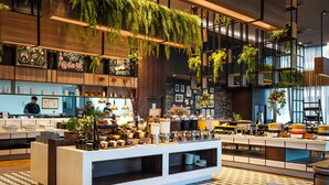 Een modern café met een geruit vloertje, houten en metalen inrichting, en hangplanten.