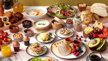 Una mesa con diversos productos para el desayuno, como pasteles, frutas y bebidas.