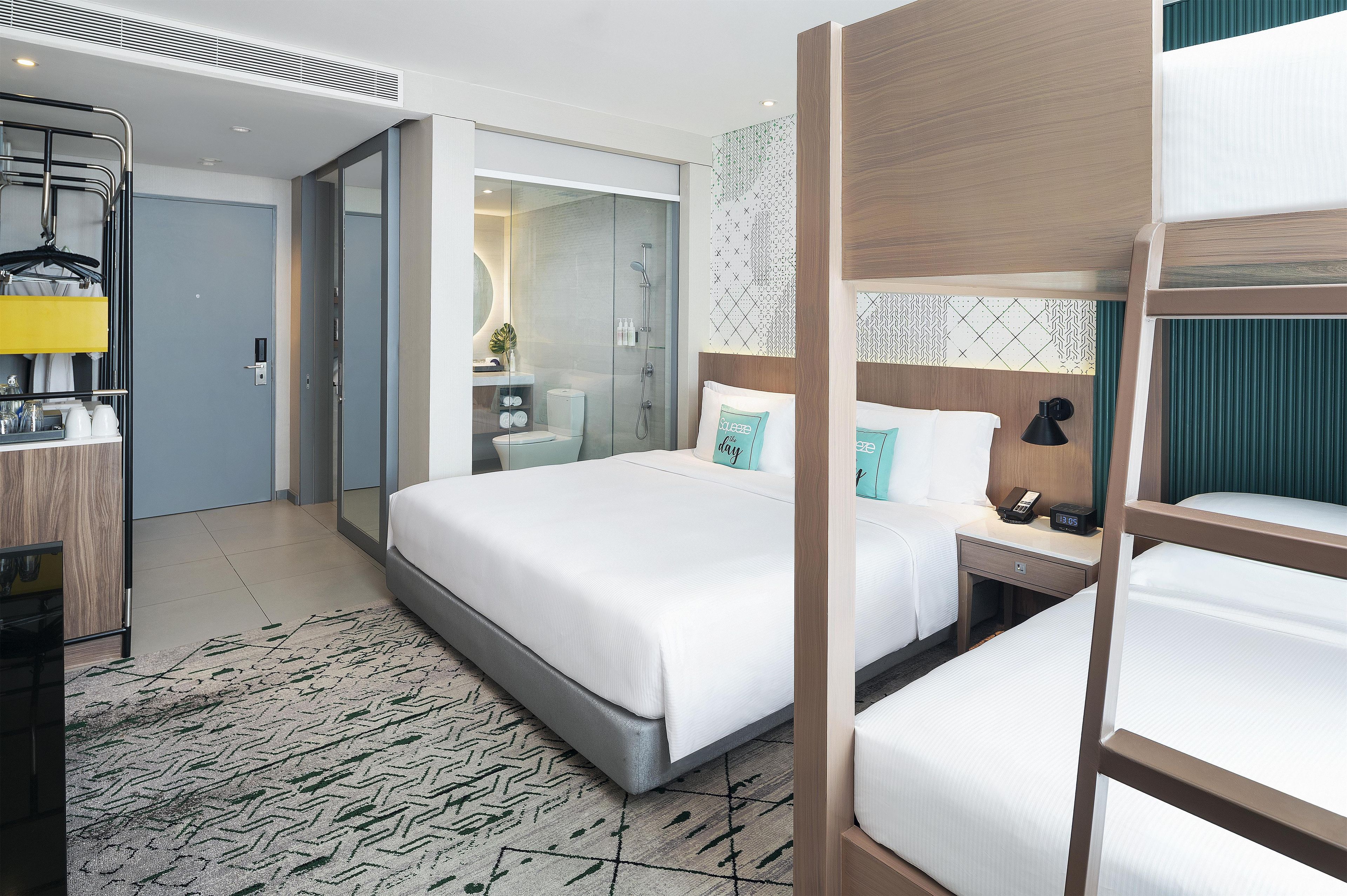 A hotel room with a large bed, a bedside table with a lamp, a mirror, and a bathroom with a shower and toilet.