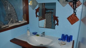 Ein Badezimmer mit einem weißen Waschbecken, einem Spiegel und einer Ablage für Toilettenartikel.