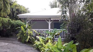 Ein Haus mit weißer Veranda, umgeben von üppigem Grün.