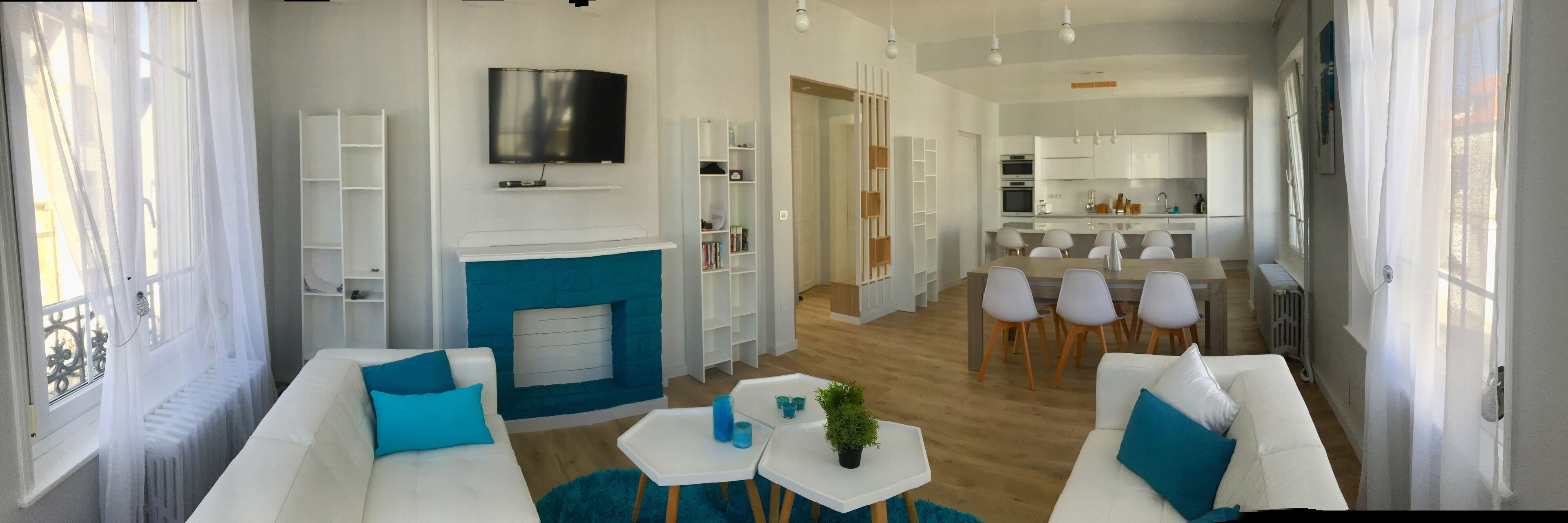 Una sala de estar moderna con chimenea, sofás blancos y un comedor con sillas.