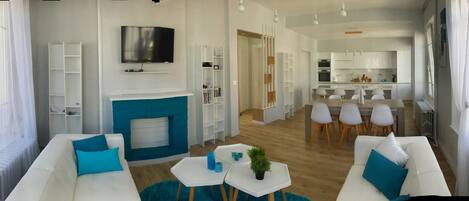 Una sala de estar moderna con chimenea, sofás blancos y un comedor con sillas.