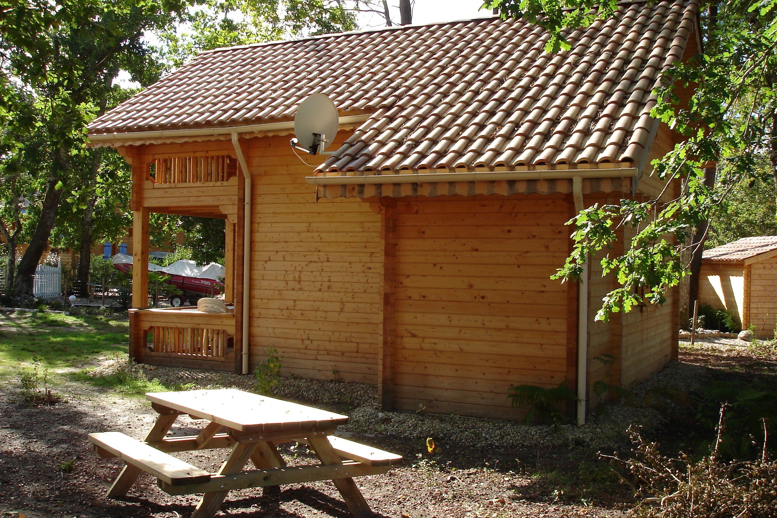Eine Holzhütte mit Ziegeldach, einem Picknicktisch und einer Satellitenschüssel.