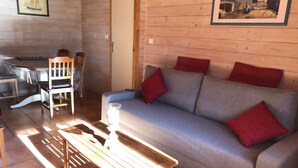 A cozy living room with a grey sofa, red cushions, a wooden coffee table, and a chair.