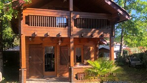 A wooden cabin with a red roof, a balcony, and a front door.