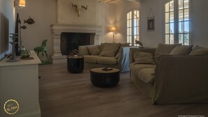 A cozy living room with a fireplace, sofas, and a coffee table. - Mas Provençal first floor living room with fireplace and veranda overlooking Alpilles- Vallée des Baux (Paradou)