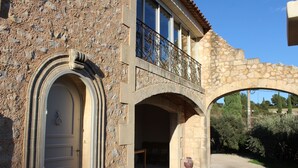A stone building with a balcony and an archway. - Mas Provençal first floor living room with fireplace and veranda overlooking Alpilles- Vallée des Baux (Paradou)