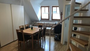 A dining area with a wooden table and chairs, a sofa, and a staircase. - Wendlers Ferienwohnungen 1 (Schwaig bei Nuernberg)