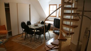 A dining area with a table and chairs, a television, and a staircase. - Wendlers Ferienwohnungen 1 (Schwaig bei Nuernberg)
