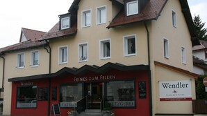 A two-story building with a red and beige facade, featuring the name 'Wendler' and 'Feines Zum Feiern' signage. - Wendlers Ferienwohnungen 1 (Schwaig bei Nuernberg)
