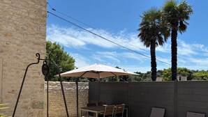 Une terrasse extérieure avec une table et des chaises, une balançoire et un palmier.
