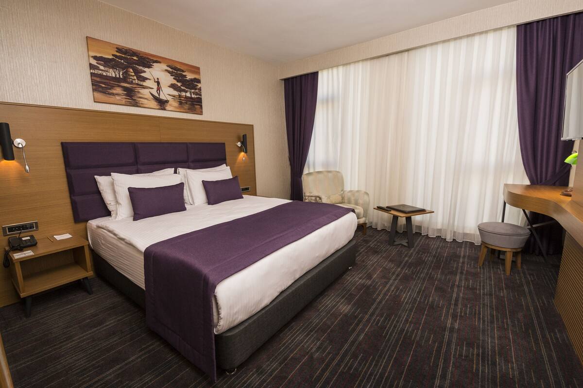 Een hotelkamer met een groot bed, een bureau, een stoel en een klein tafeltje.