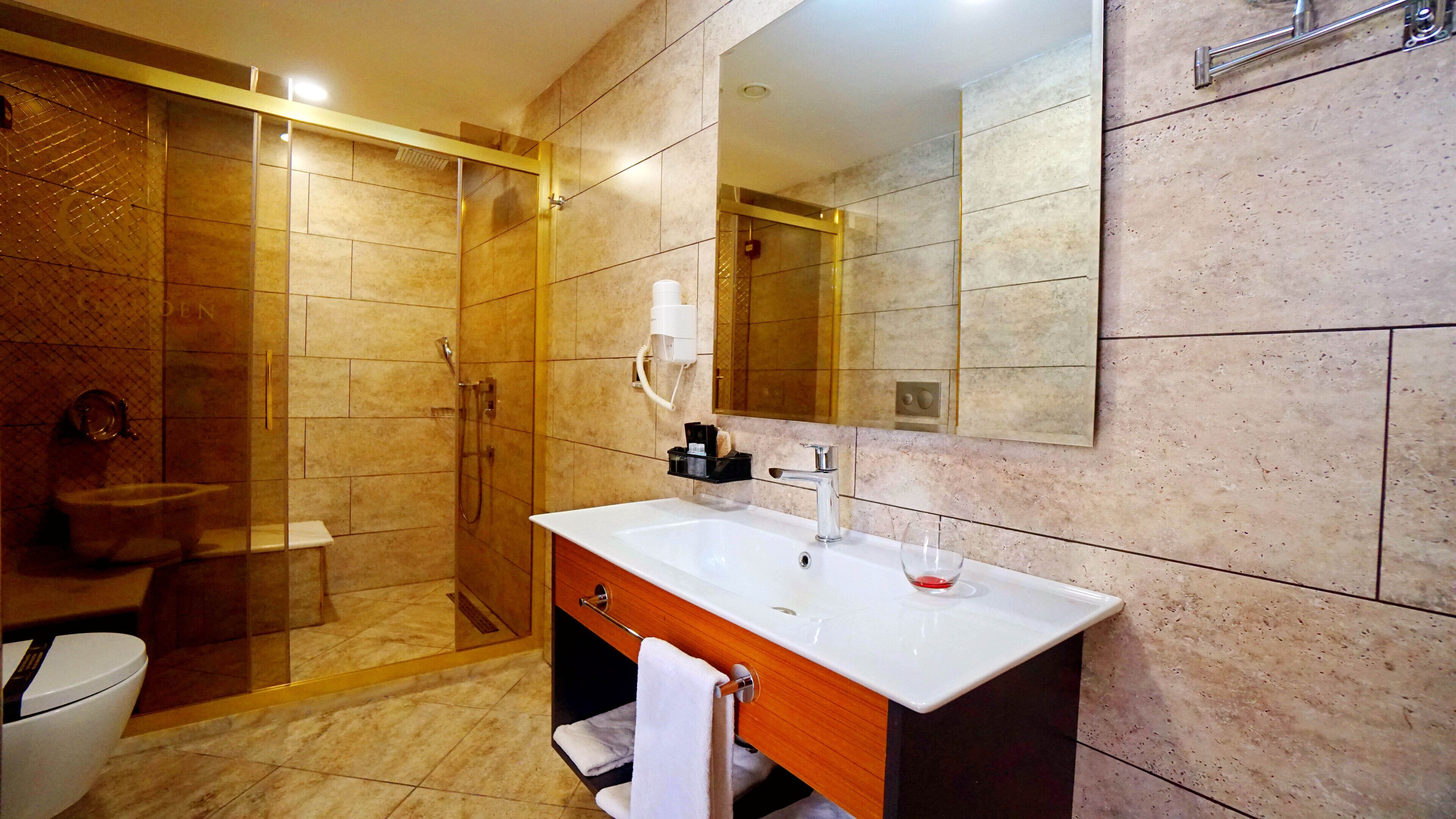 A modern bathroom with a glass-enclosed shower, a white sink, and a large mirror.