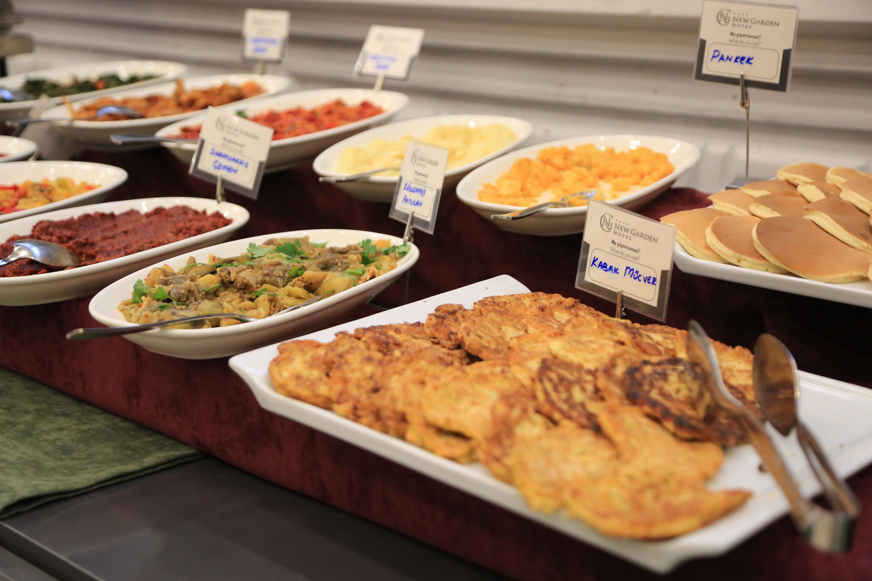 A buffet with various dishes including pancakes, a salad, and a meat dish.