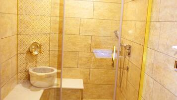 A shower area with a glass door, a white sink, and a toilet.