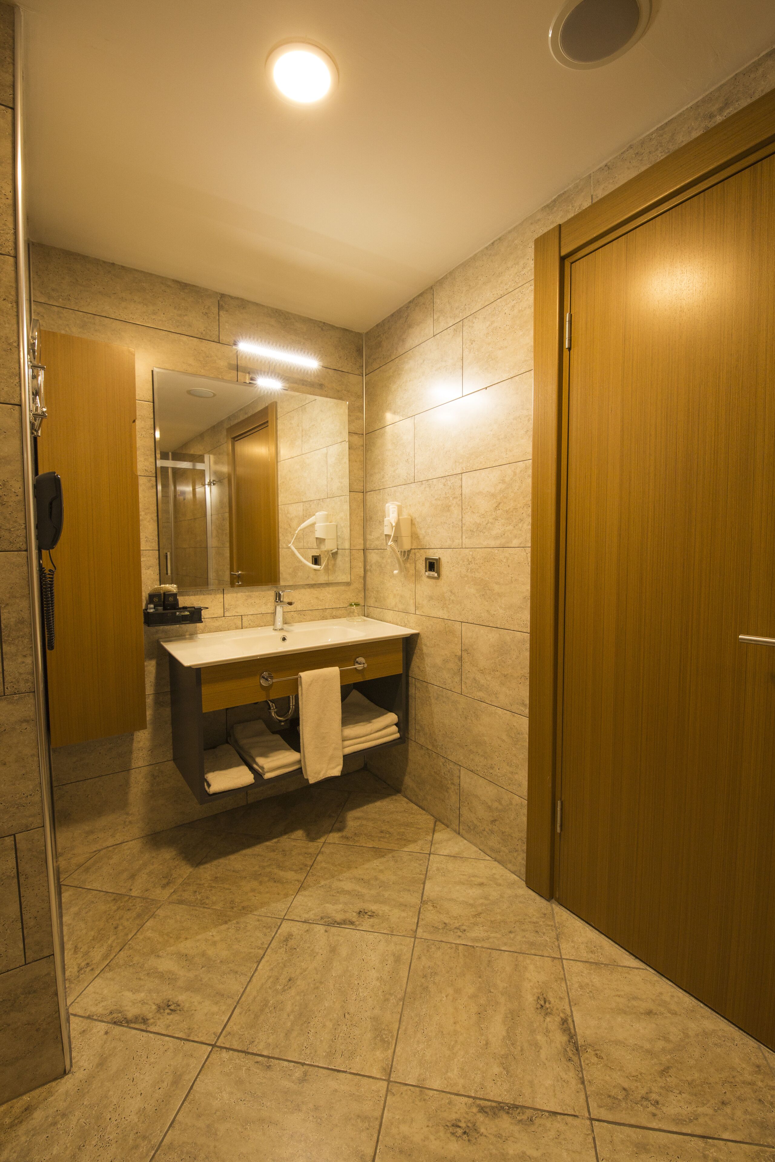 Une salle de bain avec un meuble-lavabo en bois, un miroir, un évier et un espace douche.