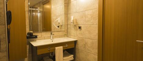 Une salle de bain avec un meuble-lavabo en bois, un miroir, un évier et un espace douche.