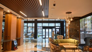 Un hall d’entrée moderne avec un sol ciré, un espace salon et de grandes fenêtres.