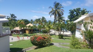 A resort with multiple bungalow-style buildings, a well-maintained lawn, and palm trees. - Anse des rochers - Studio Cashew (saint-françois)