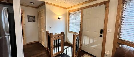 A hallway with wooden flooring, a wooden railing, and a door with a window.