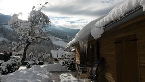 Una cabana de fusta amb entorns coberts de neu, un balcó de fusta i vistes a les muntanyes circumdants.