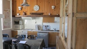 Cocina compacta con armarios de madera, microondas, cafetera y un lavamanos.