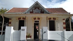 Un edificio con techo de tejas, una entrada central con puerta y un letrero encima de la entrada.