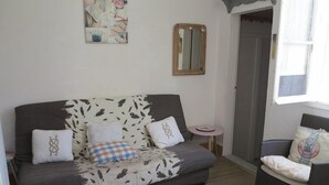 Una sala de estar acogedora con un sofá, una mesita redonda y un sillón de mimbre.
