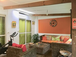 A cozy living room with wicker furniture, a sofa with colorful cushions, a wall clock, and a bicycle. - South Wild Villa with outdoor pool-jacuzzi and terrace, kitchen and lounge (Saint Joseph)