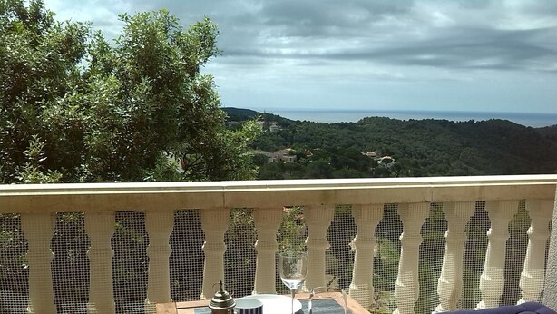 Una terraza de madera con una mesa lista para comer, con vistas panorámicas a colinas y un cuerpo de agua.