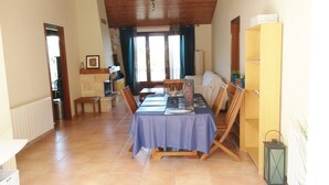 Un comedor con una mesa dispuesta para cuatro, un banco de madera, una estantería y un radiador.