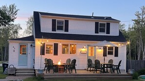 Ein zweistöckiges Haus mit Veranda und Sitzbereich im Freien.
