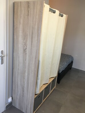 A room with a bed, a wooden wardrobe, and a curtain. - FURNITURE STUDIO IN SURGERES (SURGERES)
