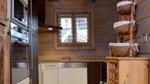 A compact kitchen with wooden walls, a built-in oven, and a window with frosted glass. - 3 room duplex (97m²) - Méribel Le Plantin - Hameau des Biches (Les Allues)
