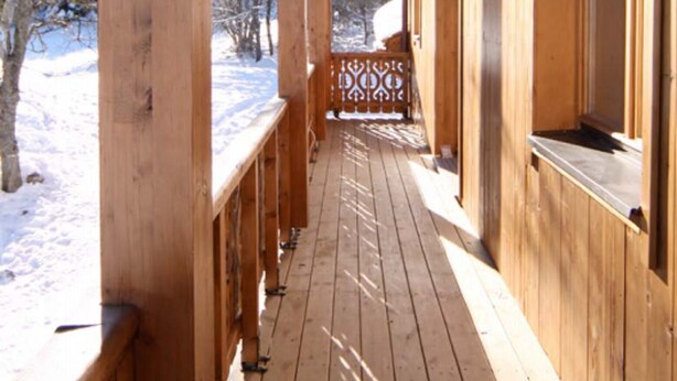 A wooden cabin with a covered porch and a window with a view of the snowy landscape. - 3 room duplex (97m²) - Méribel Le Plantin - Hameau des Biches (Les Allues)
