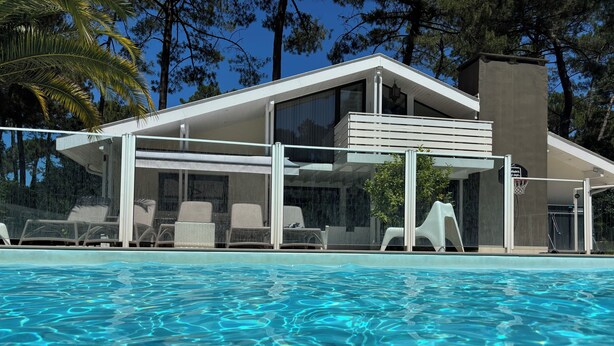 Un espace moderne aménagé au bord de la piscine, avec des chaises longues et un coin salon abrité.