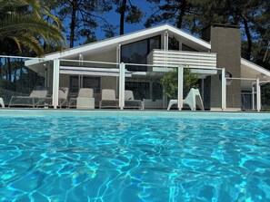 A modern poolside area with lounge chairs and a covered seating area.