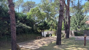 Un espace extérieur aménagé, avec des arbres, un banc en bois et un chemin pavé.