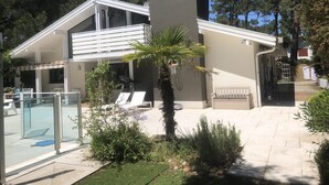 Une maison moderne dotée d’une piscine, d’un espace salon extérieur et d’un panier de basketball.