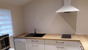 Una cocina compacta con microondas, lavavajillas y un lavabo con grifo moderno.