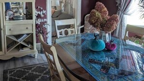 A dining area with a glass table, chairs, and a hanging light fixture. - Spacious Sunny Apt: Walk to Shop, Eat & NYC Train (Montclair)