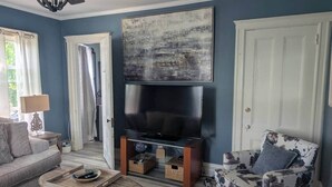 A living room with a flat-screen TV, a sofa, a patterned armchair, and a coffee table. - Spacious Sunny Apt: Walk to Shop, Eat & NYC Train (Montclair)