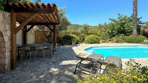 En patio med pool, flisebelægning, et pergola og udendørs møbler.