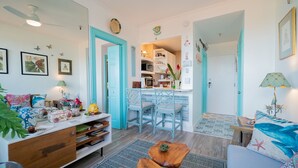 Una sala de estar acogedora con una mesa de centro de madera, un sofá y una zona de cocina con sillas azules.